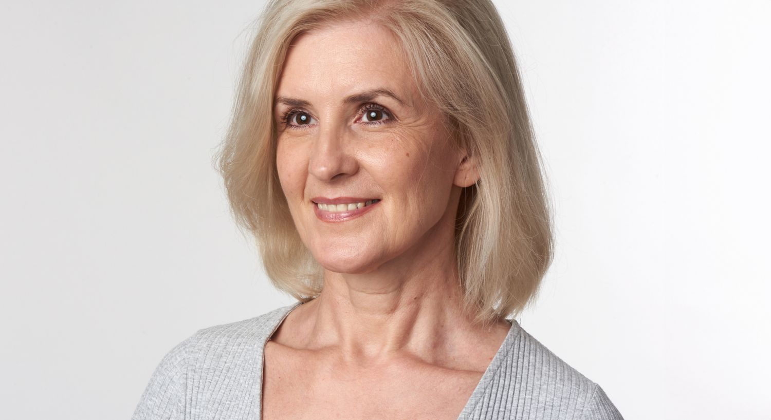 Smiling woman with blonde hair and gray top.