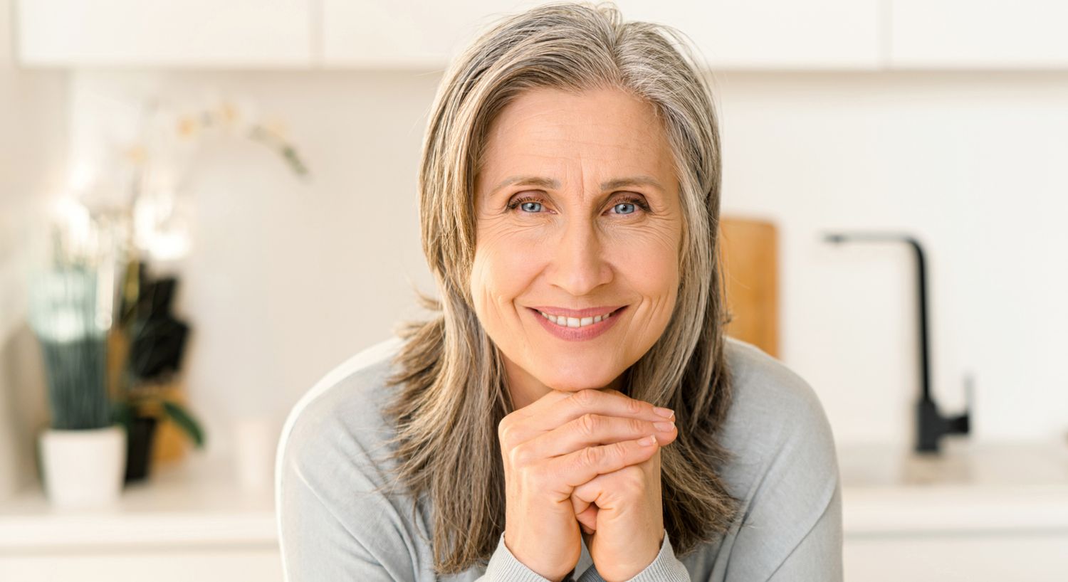 Smiling older woman in a bright kitchen.