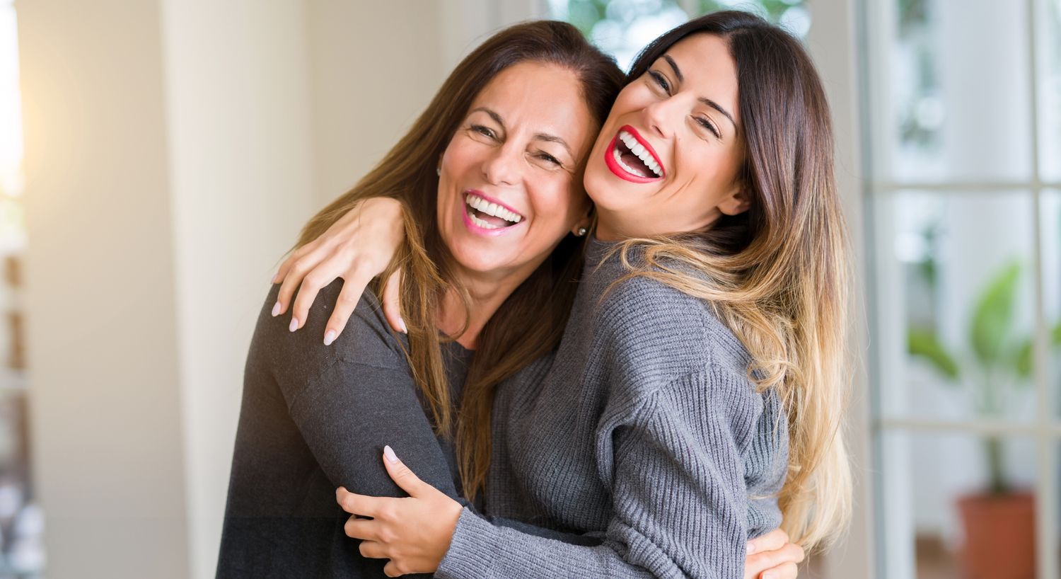 Two women smiling and embracing joyfully.