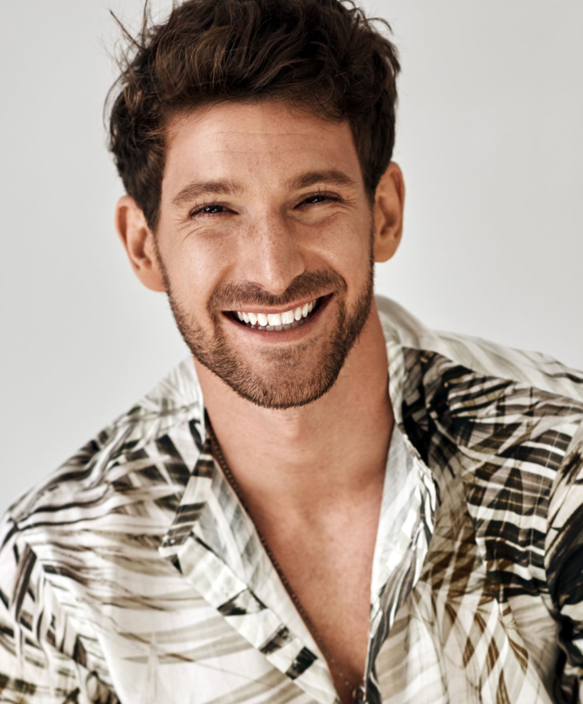 Smiling man wearing a patterned shirt.