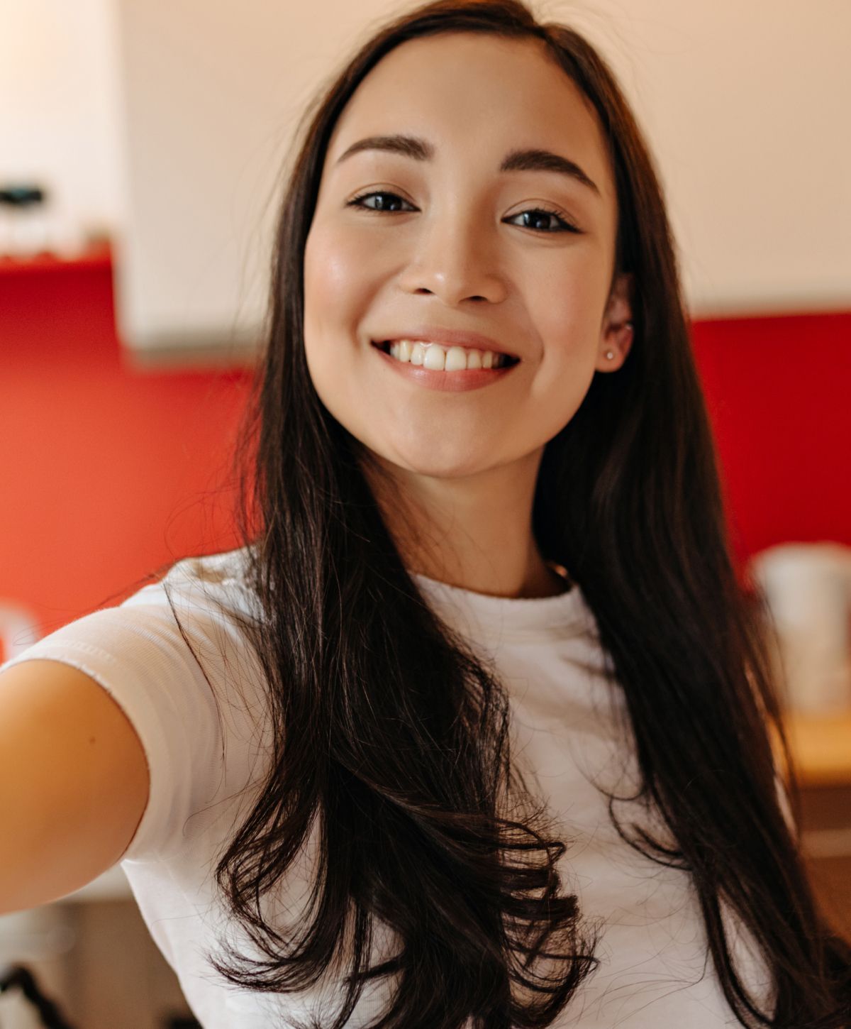 Smiling woman taking a selfie indoors.