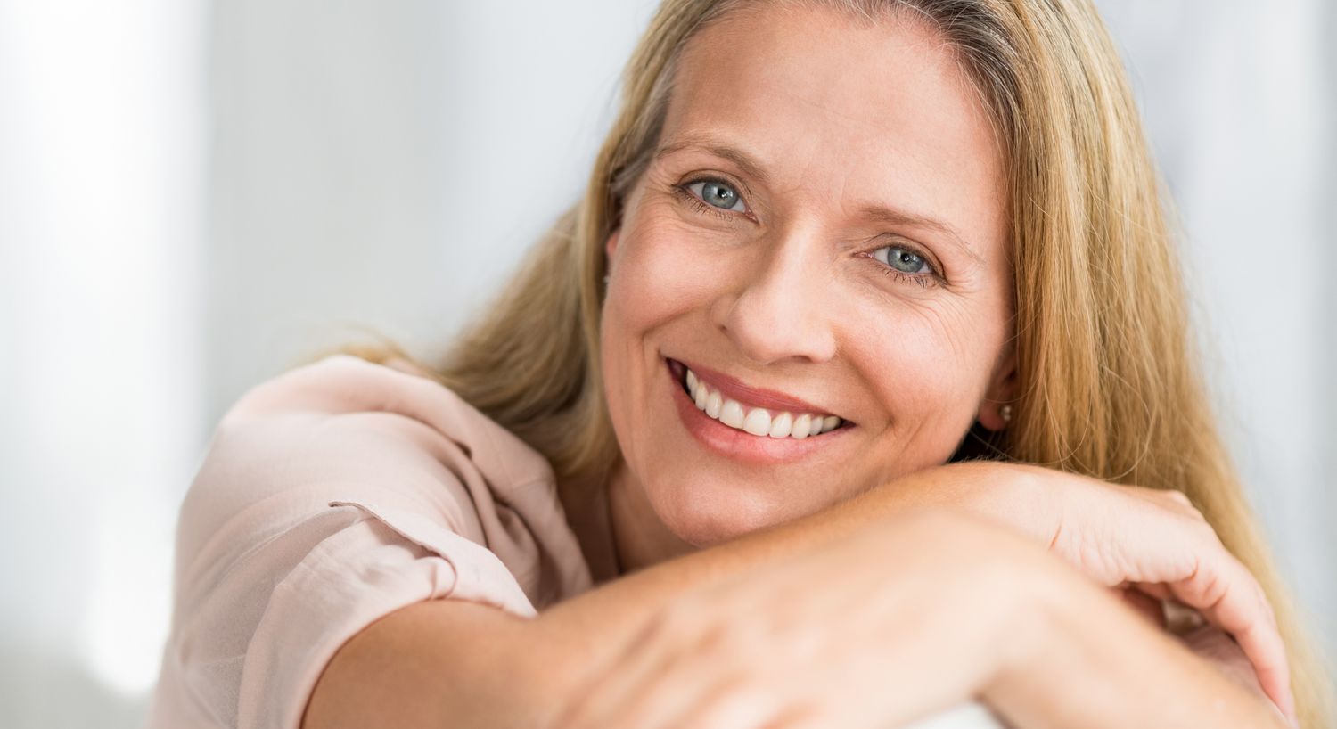 Smiling woman with long hair against gray background.