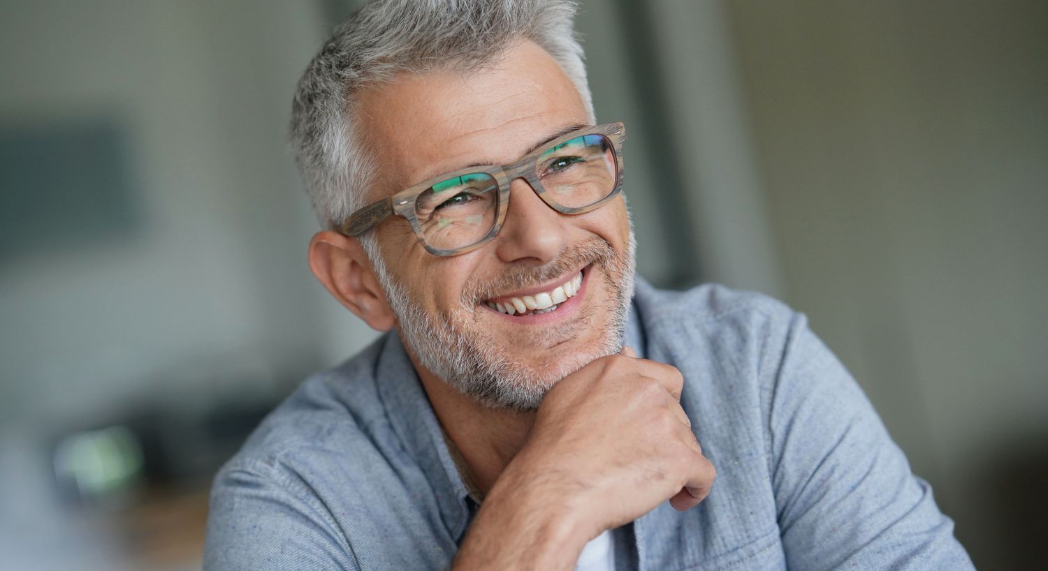 Smiling older man with glasses indoors.