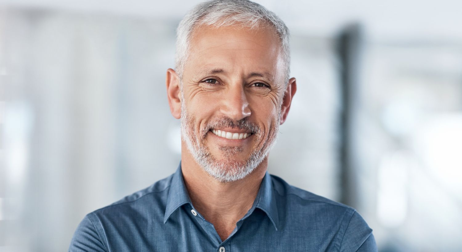 Smiling man with gray hair in a blue shirt.