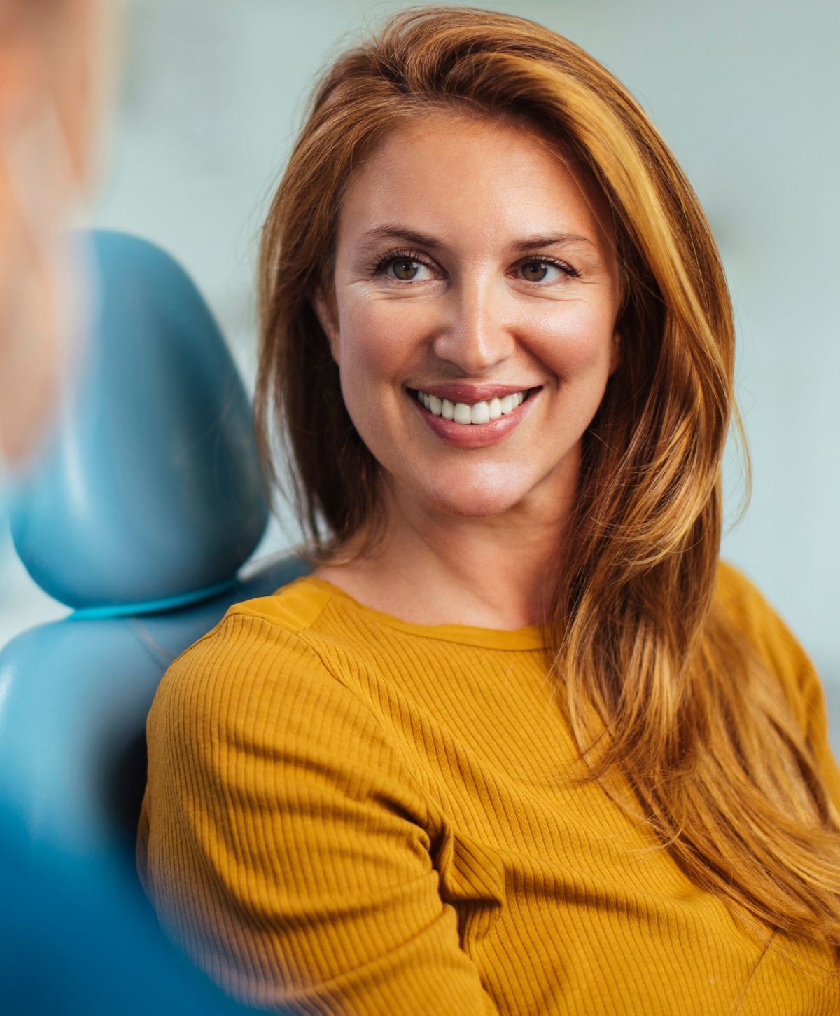 Smiling woman in a yellow top, relaxed expression.