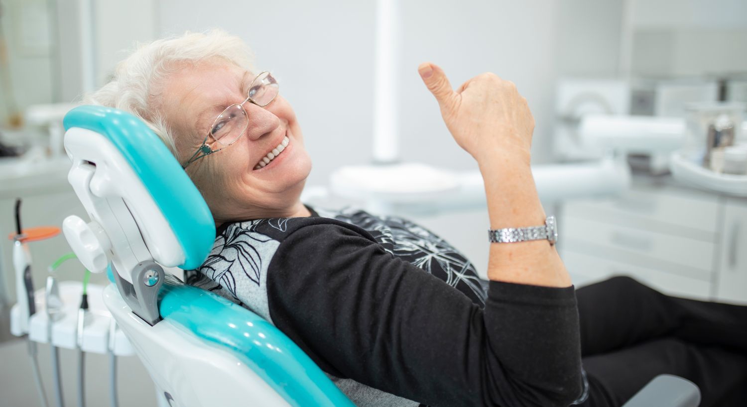 Senior woman smiling in dental office chair.