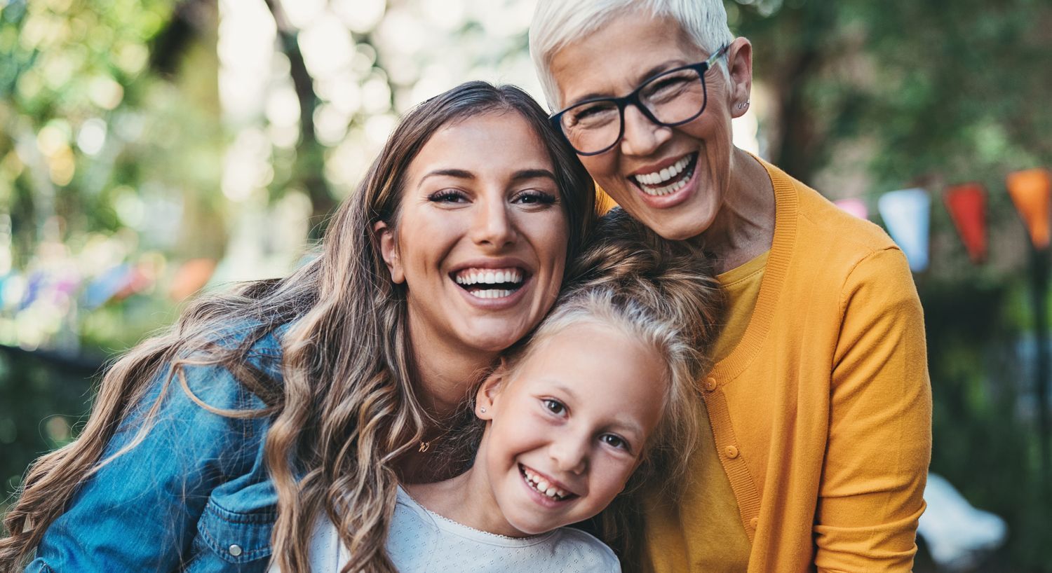 Three generations smiling together outdoors.