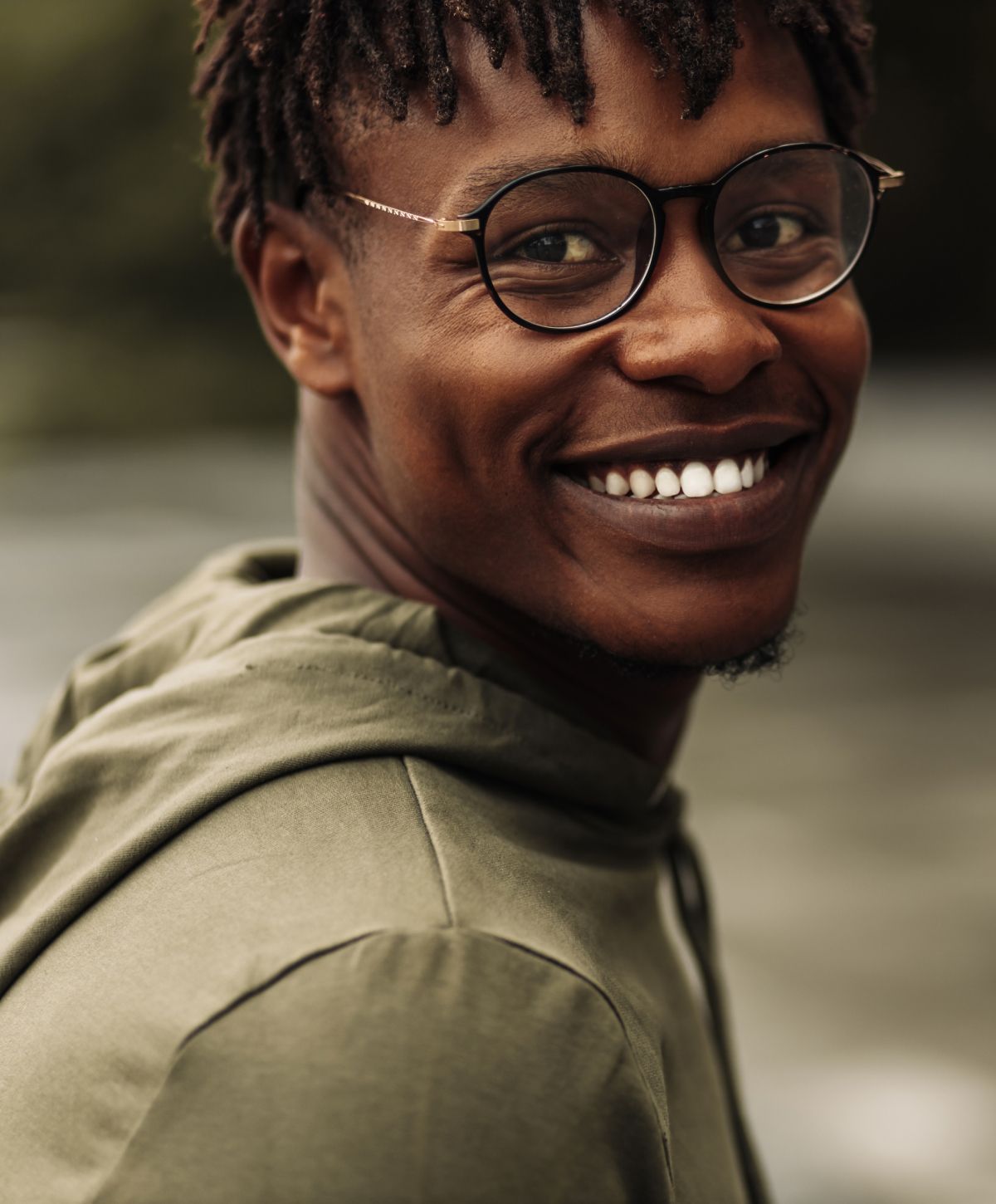 Smiling man with glasses in nature setting.