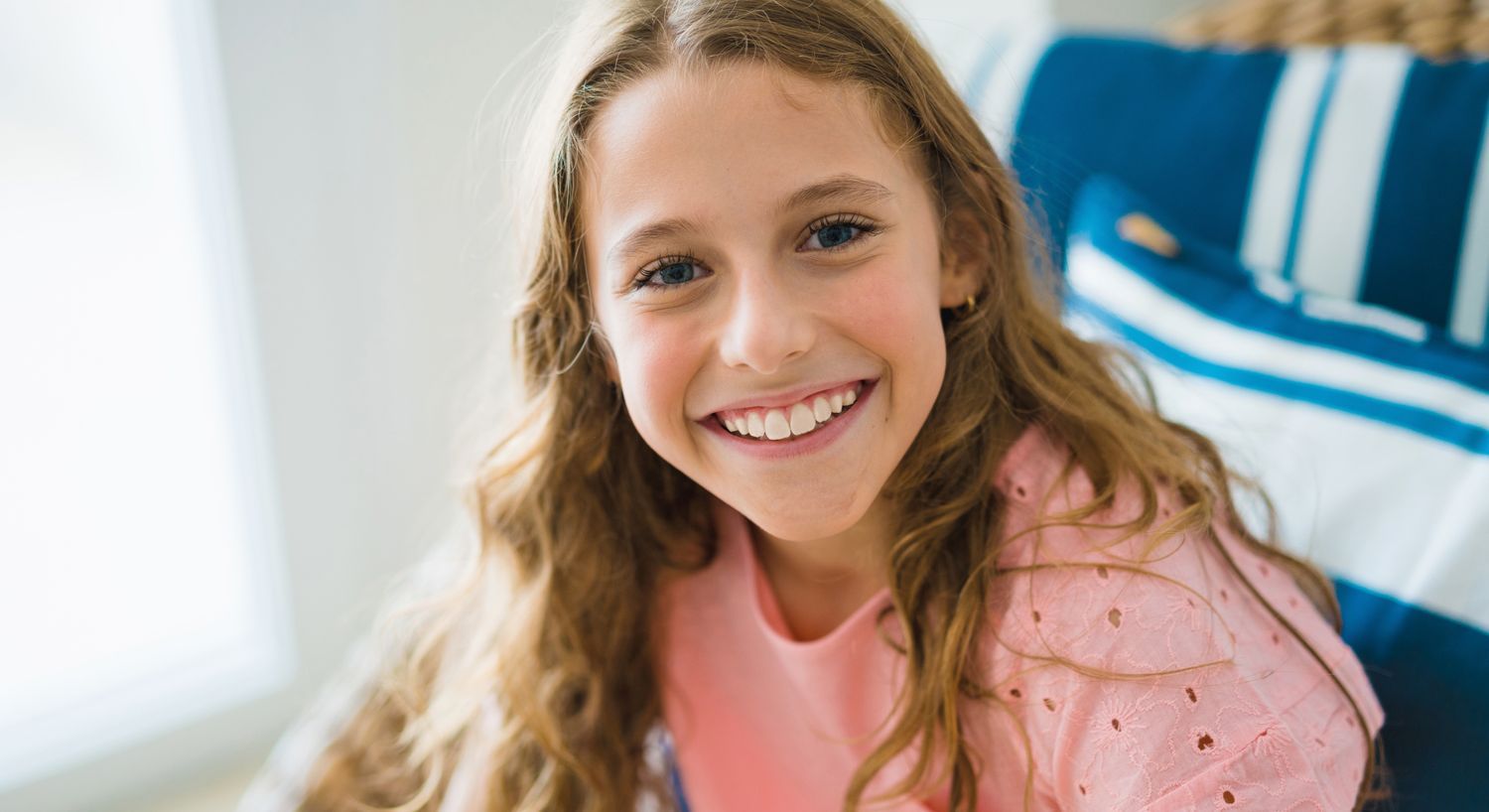 Smiling girl with wavy hair indoors.